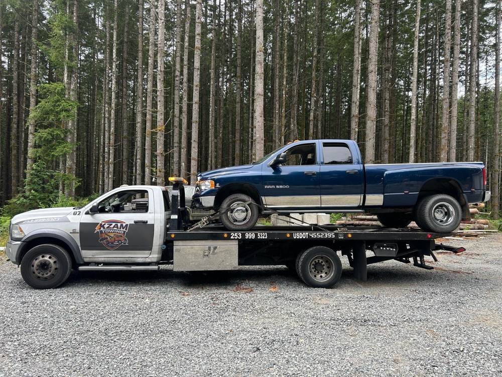 KZAM flatbed truck transporting a vehicle