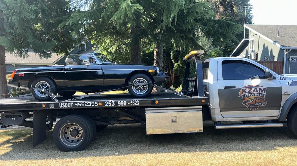 KZAM flatbed hauling a white BMW